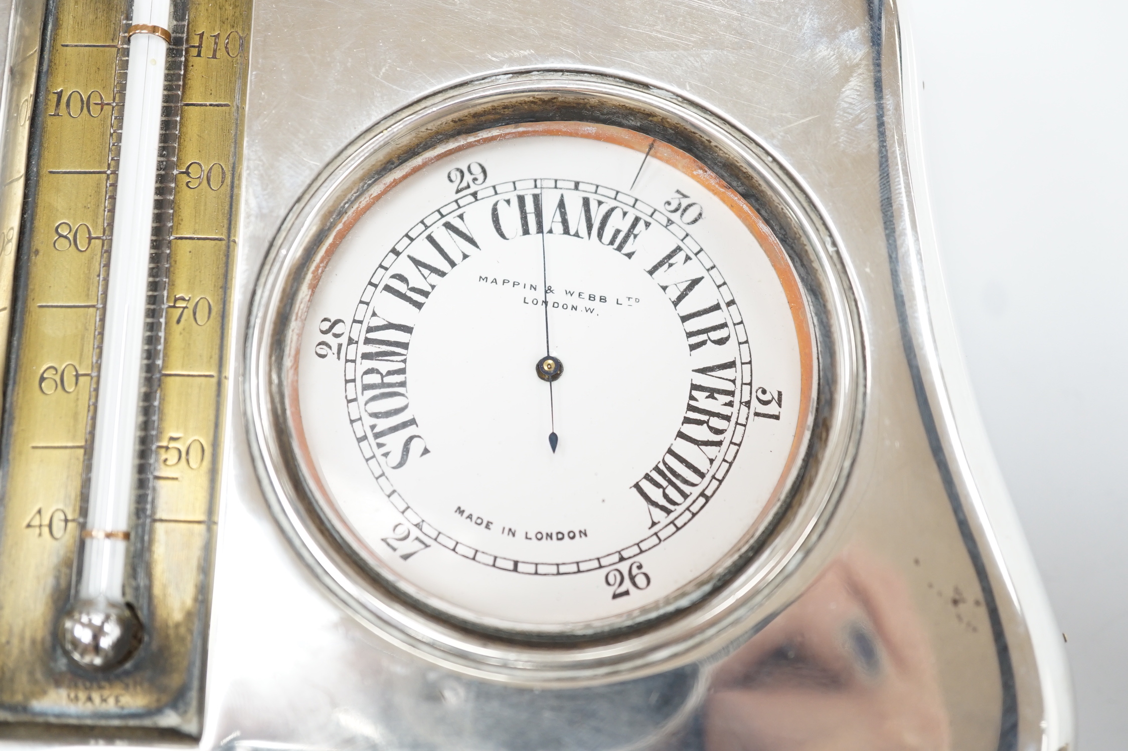 An Edwardian silver mounted leather clock/barometer desk stand, containing a pocket watch, retailed by Mappin & Webb, a similar barometer and a central thermometer, Henry Matthews, Birmingham, 1905, width 21.2cm.